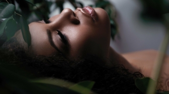 Closeup portrait of a beautiful metis woman with perfect smooth glowing mulatto skin, full lips and black hair. An african american female model with fresh makeup on her face. Verdure and beauty